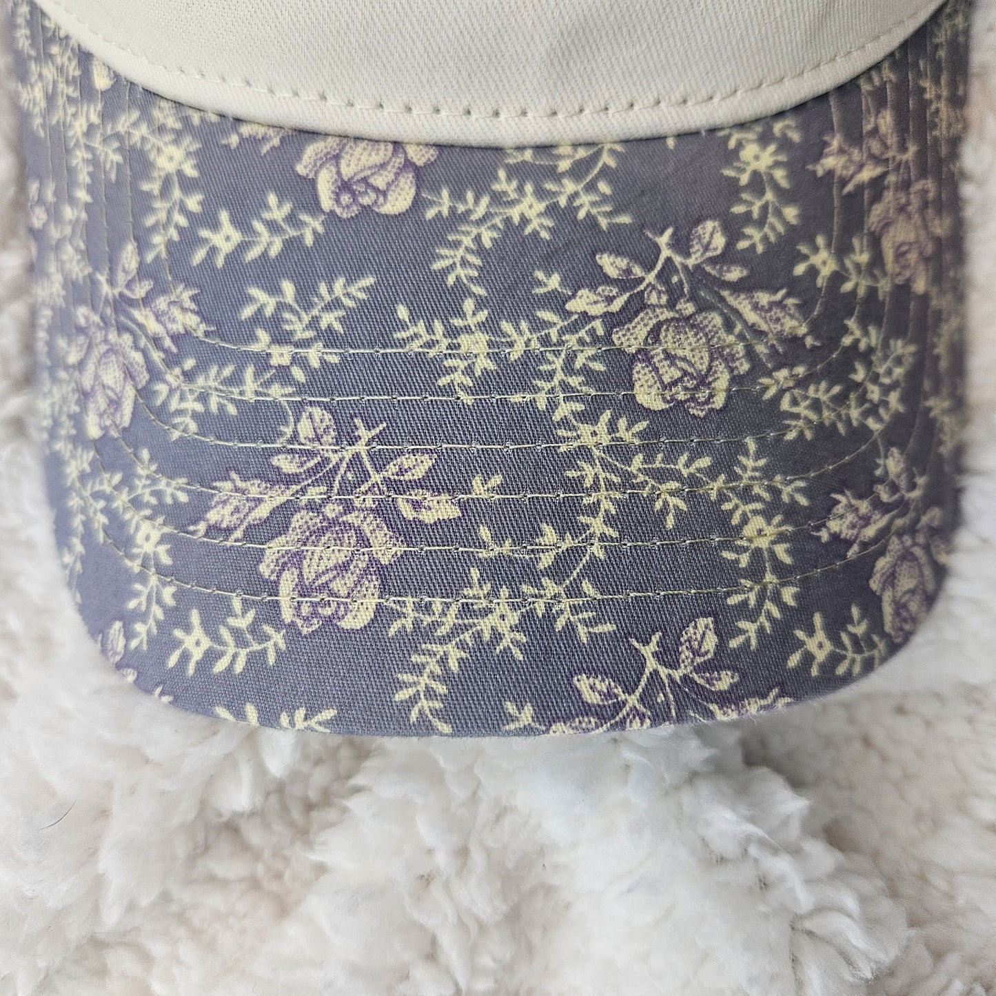 Floral patterned hat bill on a textured surface
