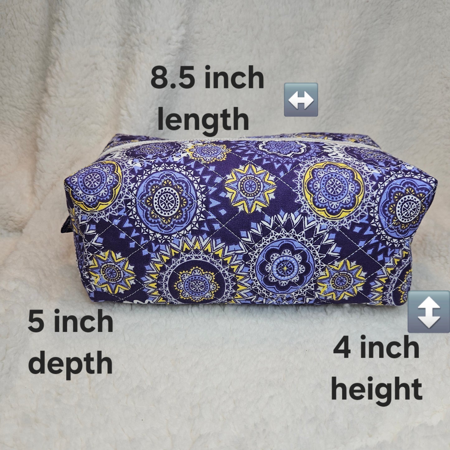 Purple patterned toiletry bag with measurements on a gray background