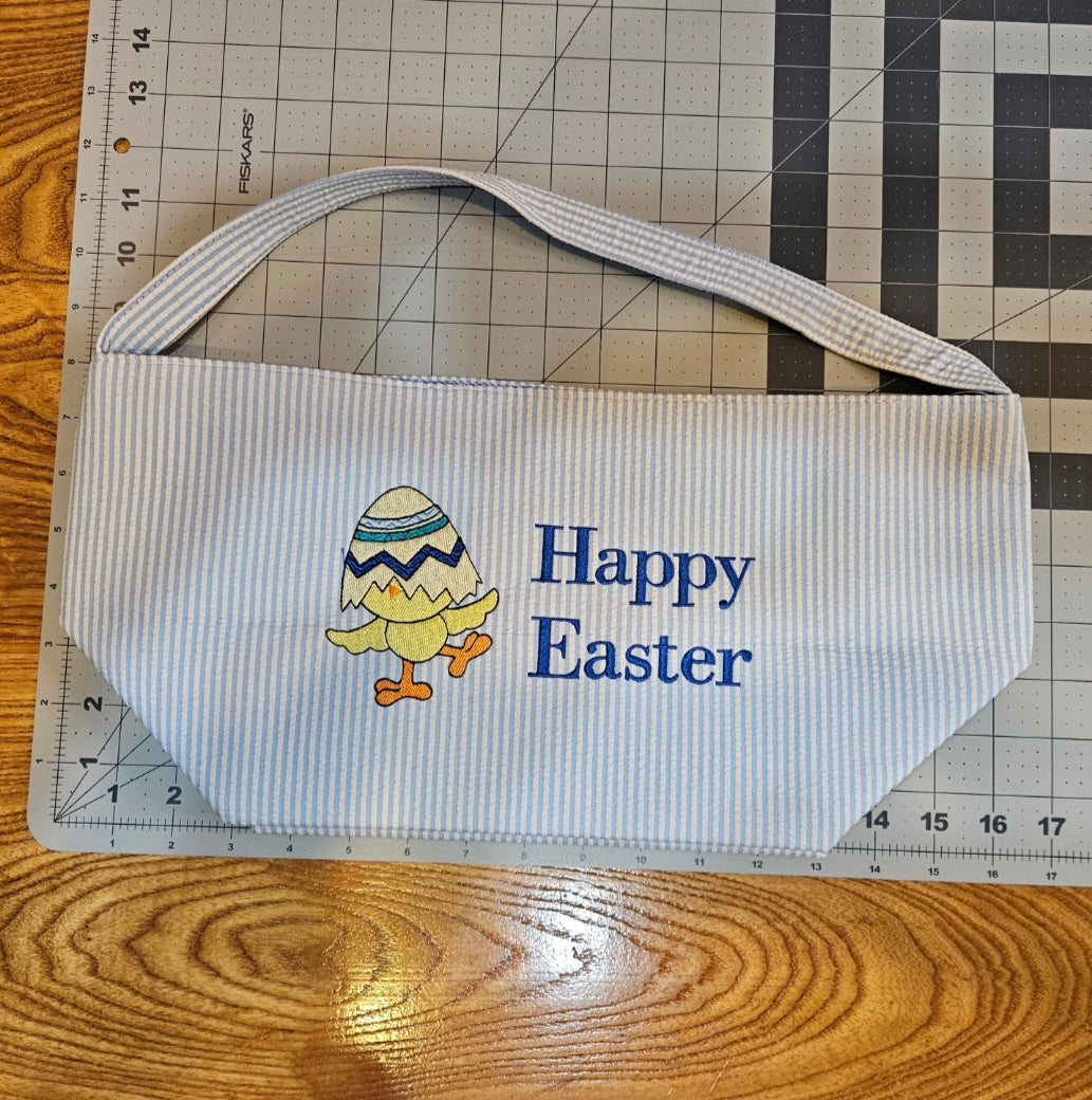 Embroidered basket with 'Happy Easter' text and chick design on a cutting mat.