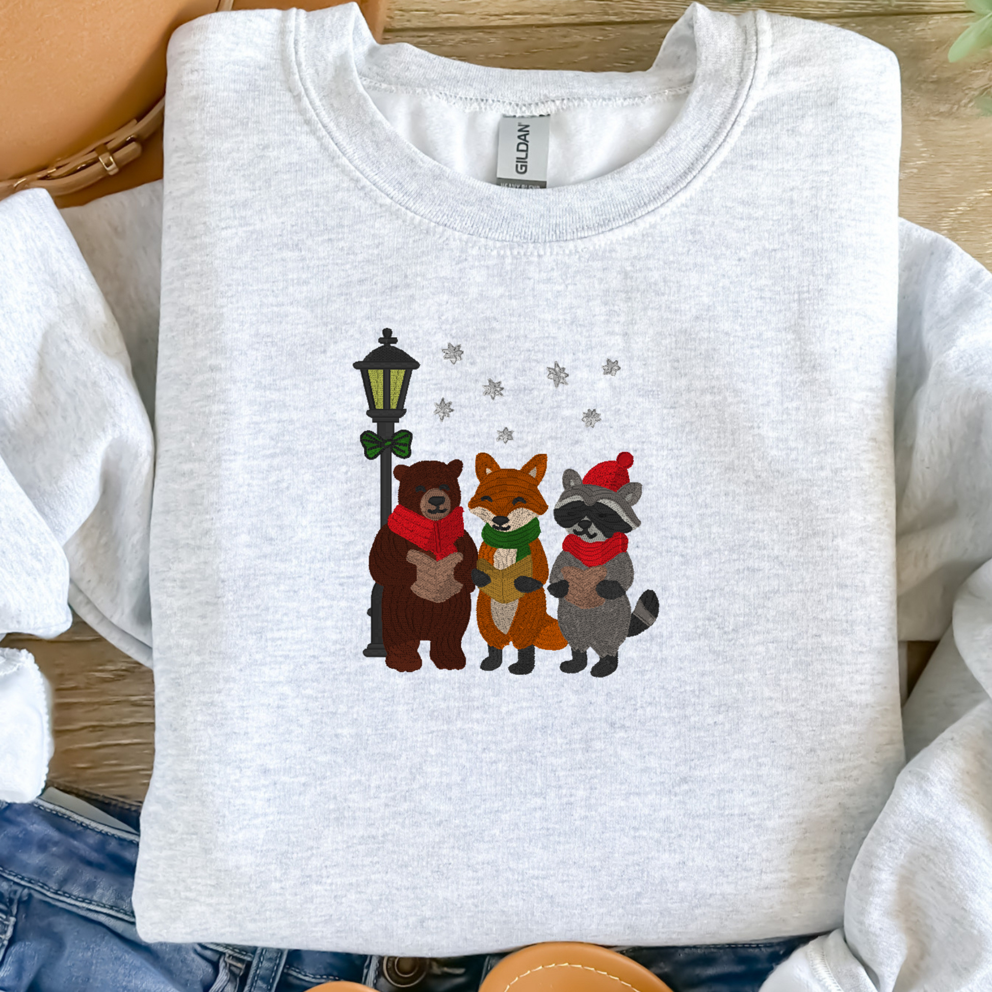 Ash gray sweatshirt with embroidered animals on a wooden surface