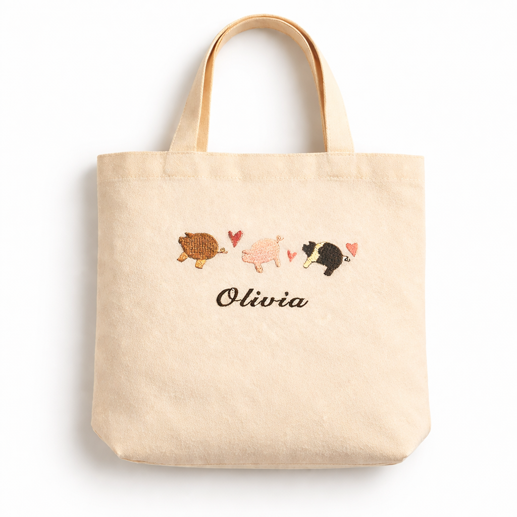 Natural tote bag with embroidered pigs and the name 'Olivia' on a white background