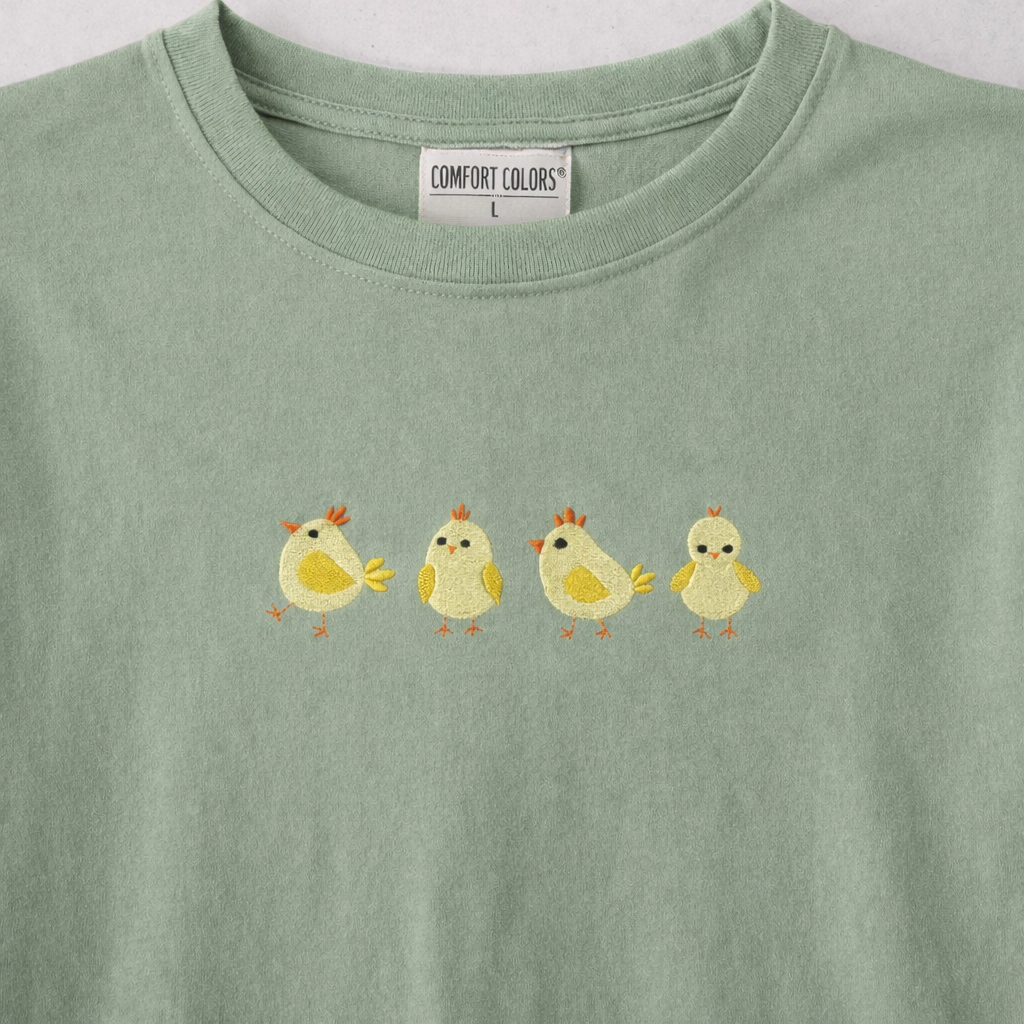 Sage t-shirt with four yellow chick design on a white background
