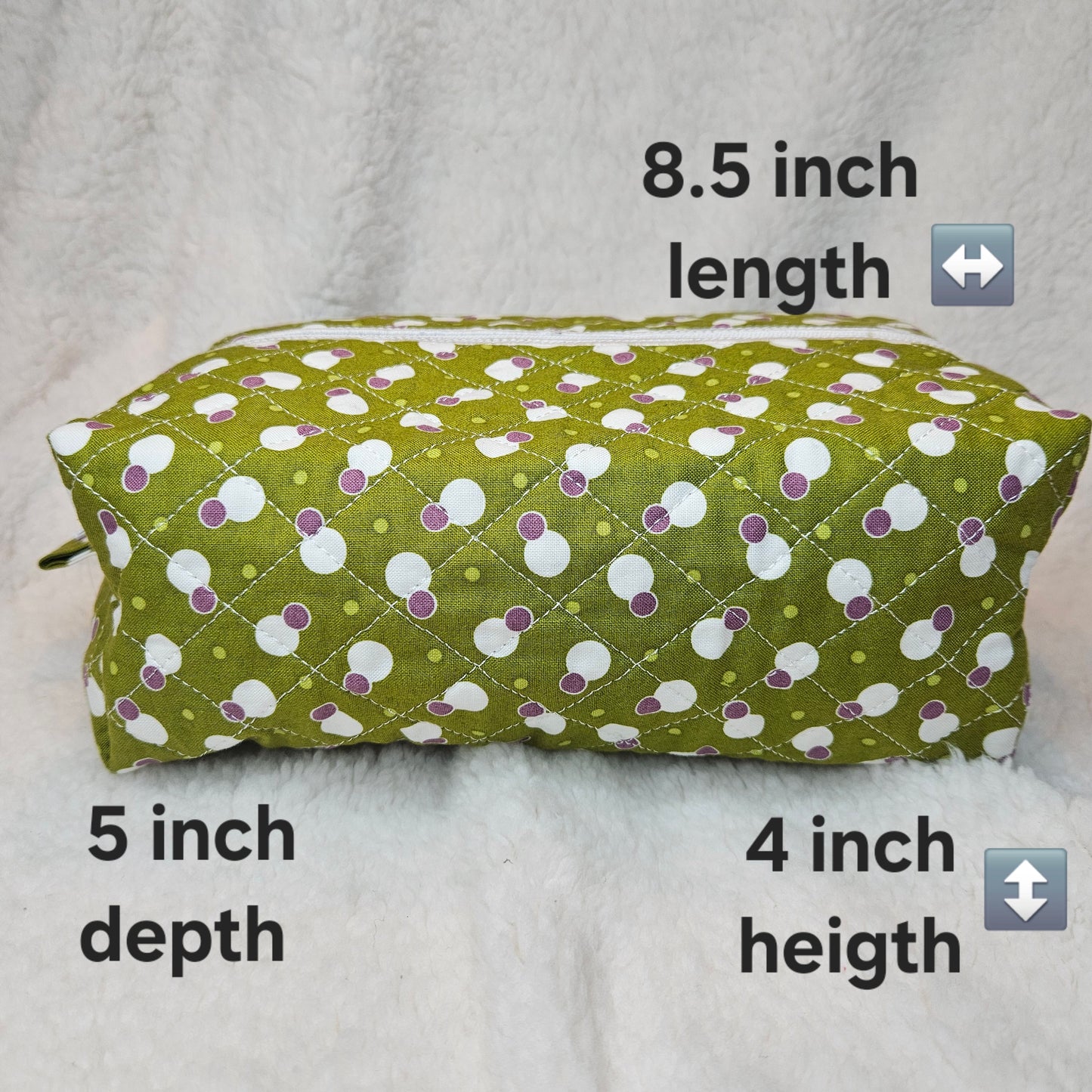 Green fabric pouch with white and purple polka dot pattern, measurements indicated on a light gray background.