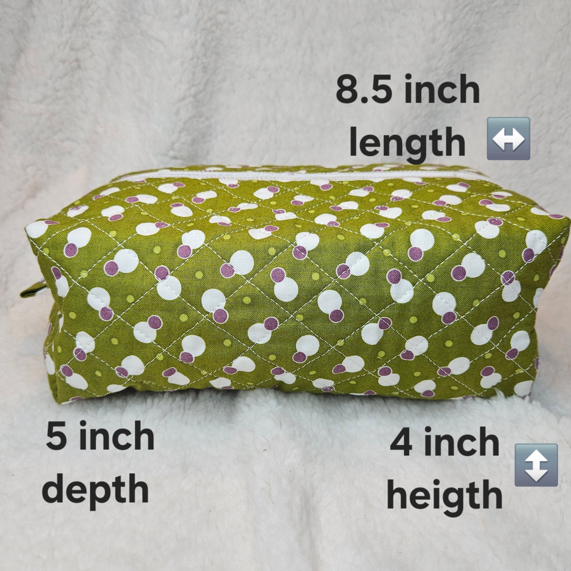 Green fabric pouch with white and purple polka dot pattern, measurements indicated on a light gray background.