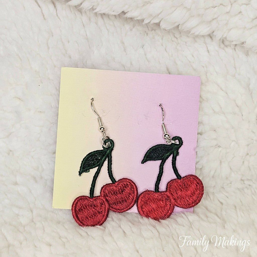 Embroidered cherry earrings with silver posts on a card