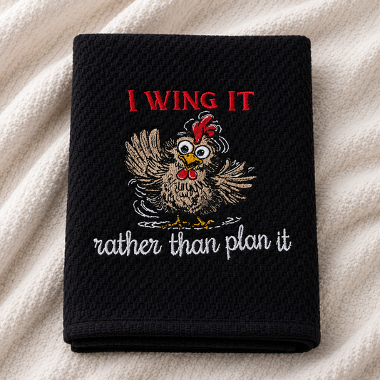 Black towel with a rooster graphic and text on a beige fabric background