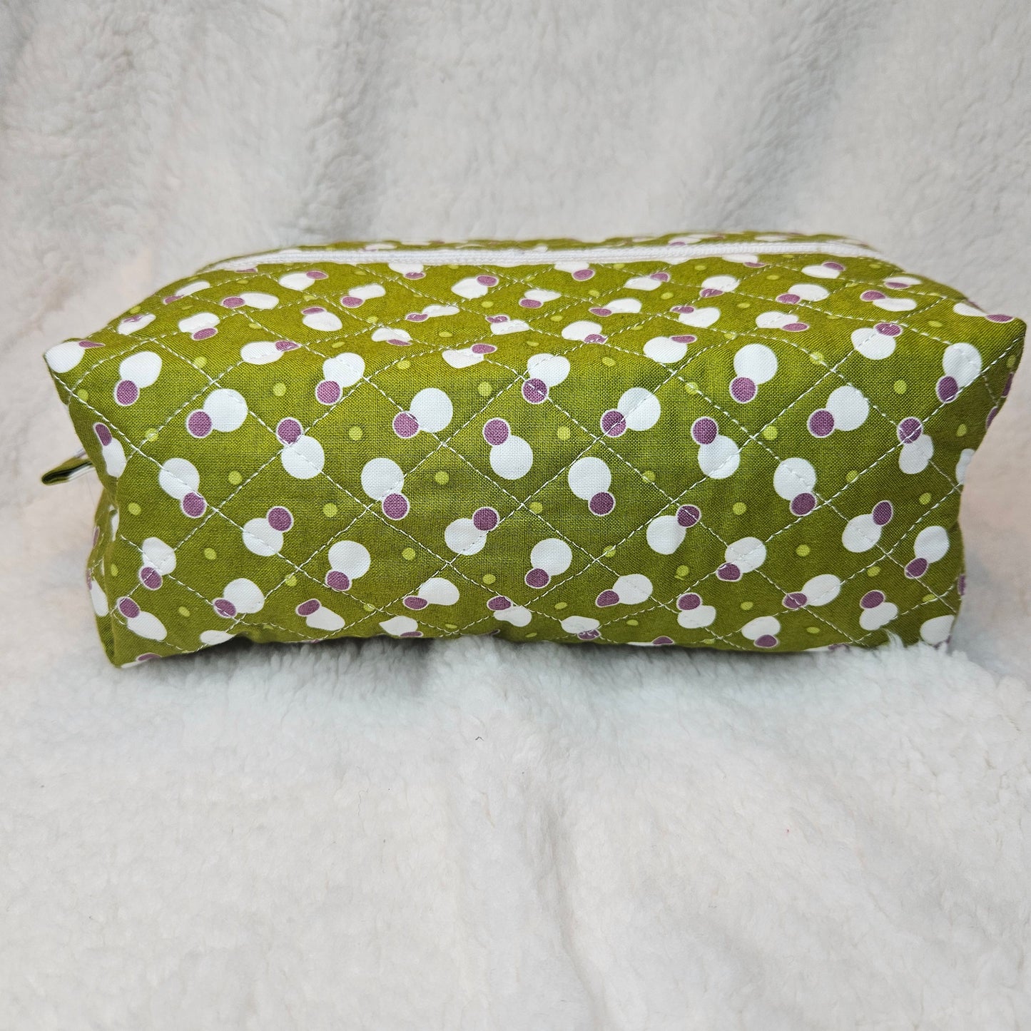 Green bag with white and purple polka dot pattern on a gray background