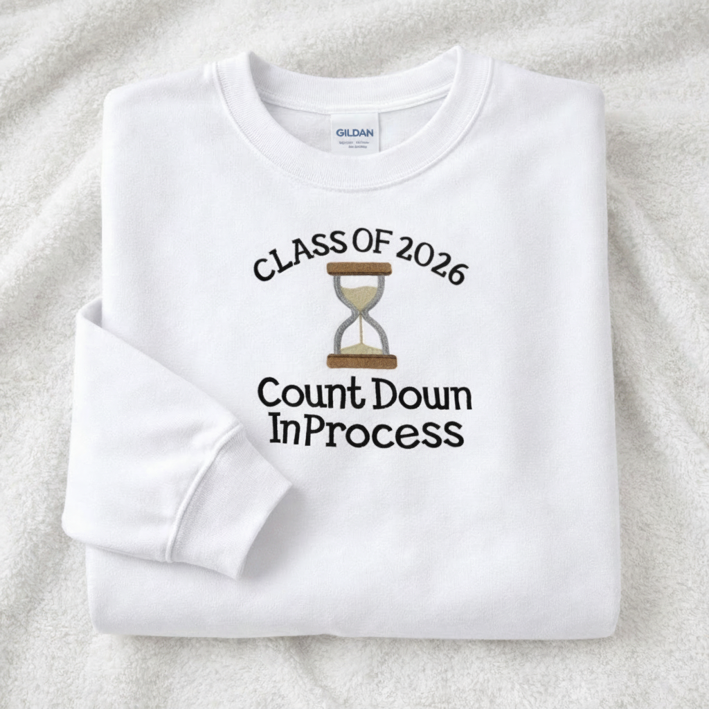 White sweatshirt with 'Class of 2026 Countdown In Process' text and sand hourglass embroidery on a white background