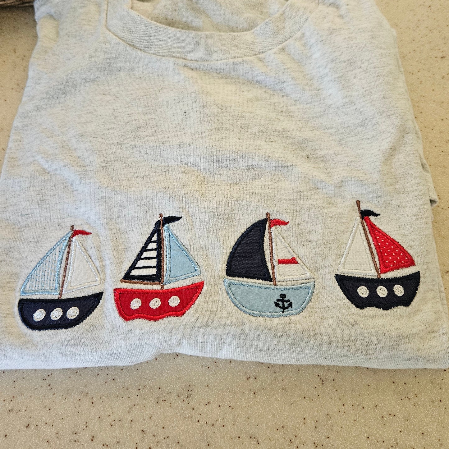 Sweatshirt with appliqué sailboat designs on a beige background