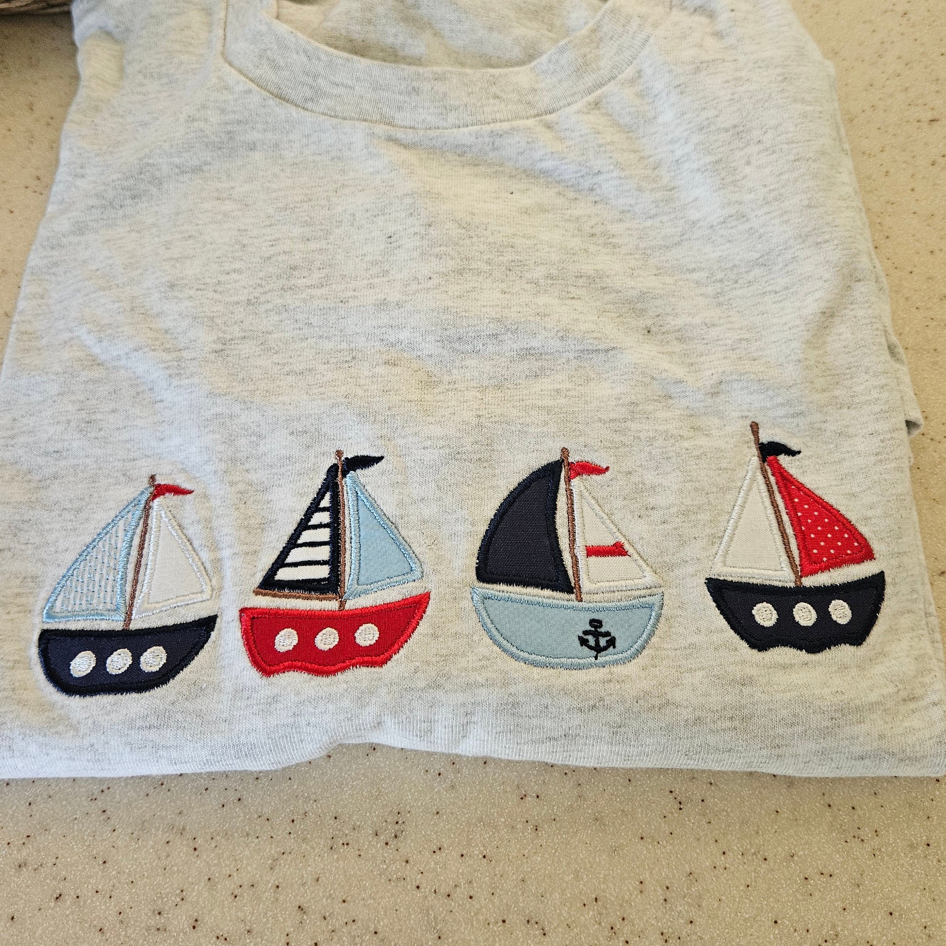 Sweatshirt with appliqué sailboat designs on a beige background