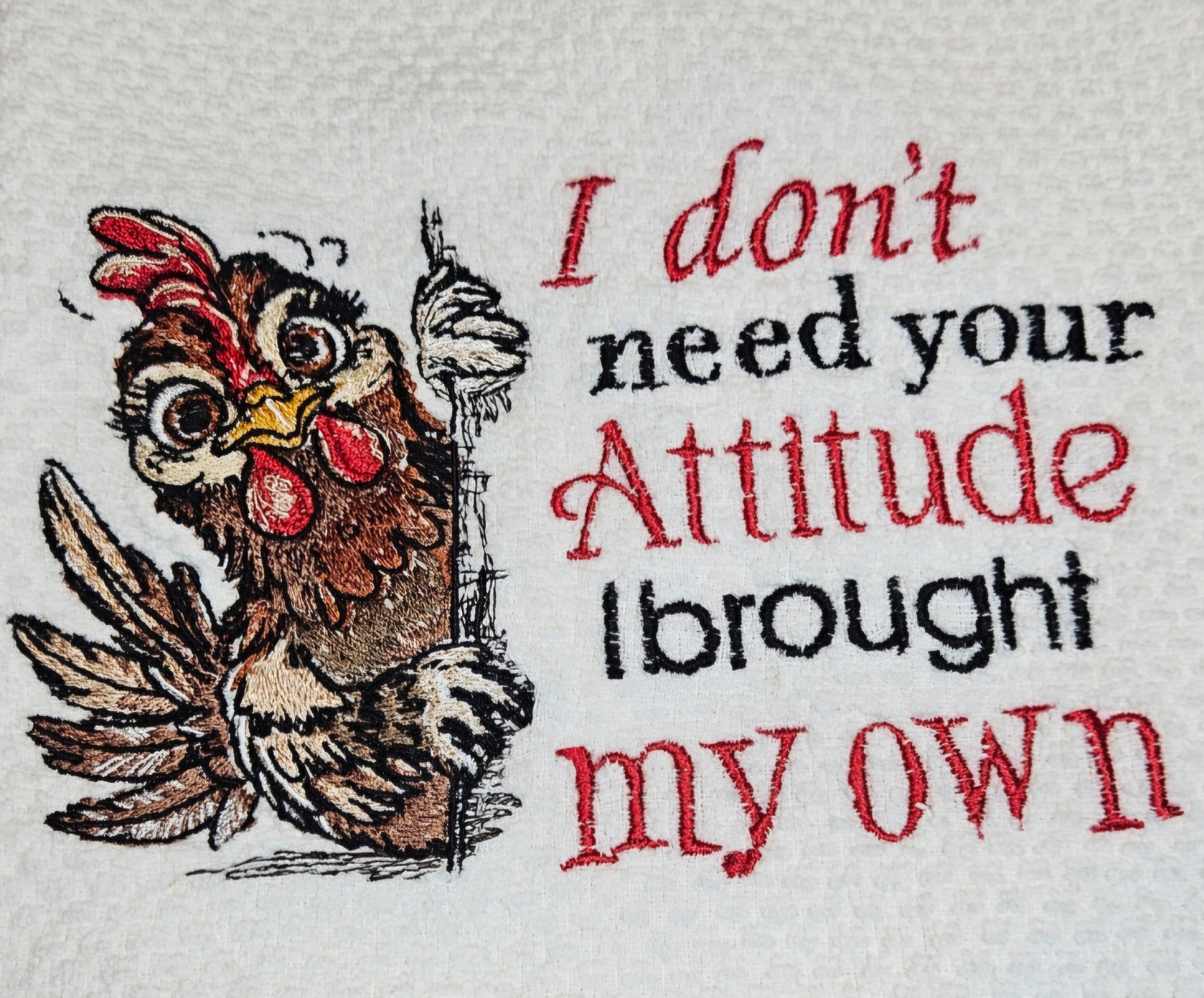Embroidery design of a rooster with text 'I don't need your attitude, I brought my own' on a white background.