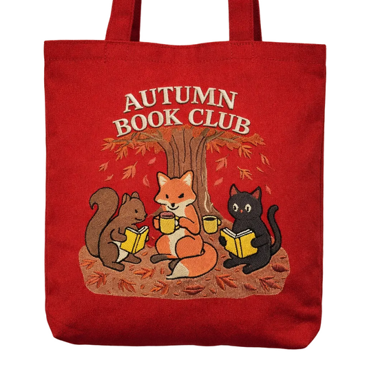 Red tote bag with autumn-themed design featuring animals reading books under a tree.