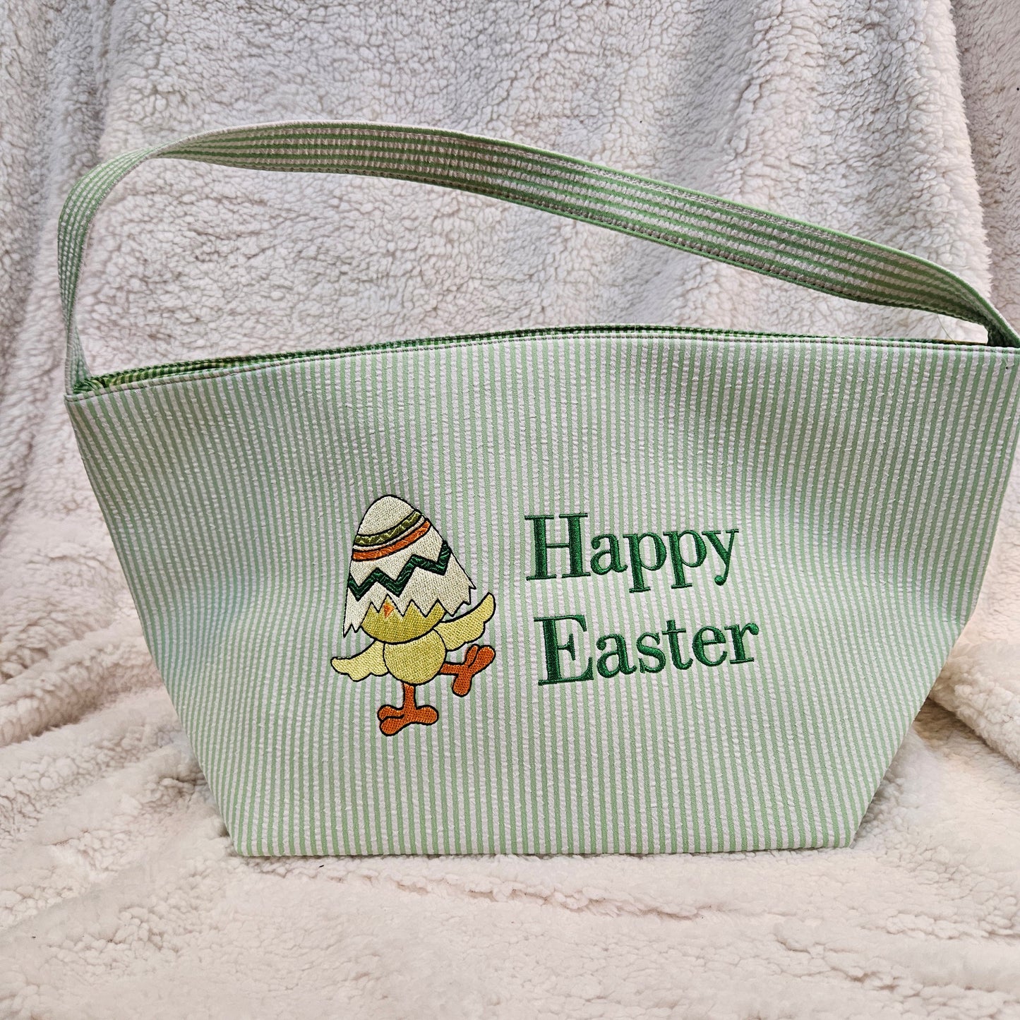 Green stripped basket with 'Happy Easter' text and chick design embroidered on a textured surface