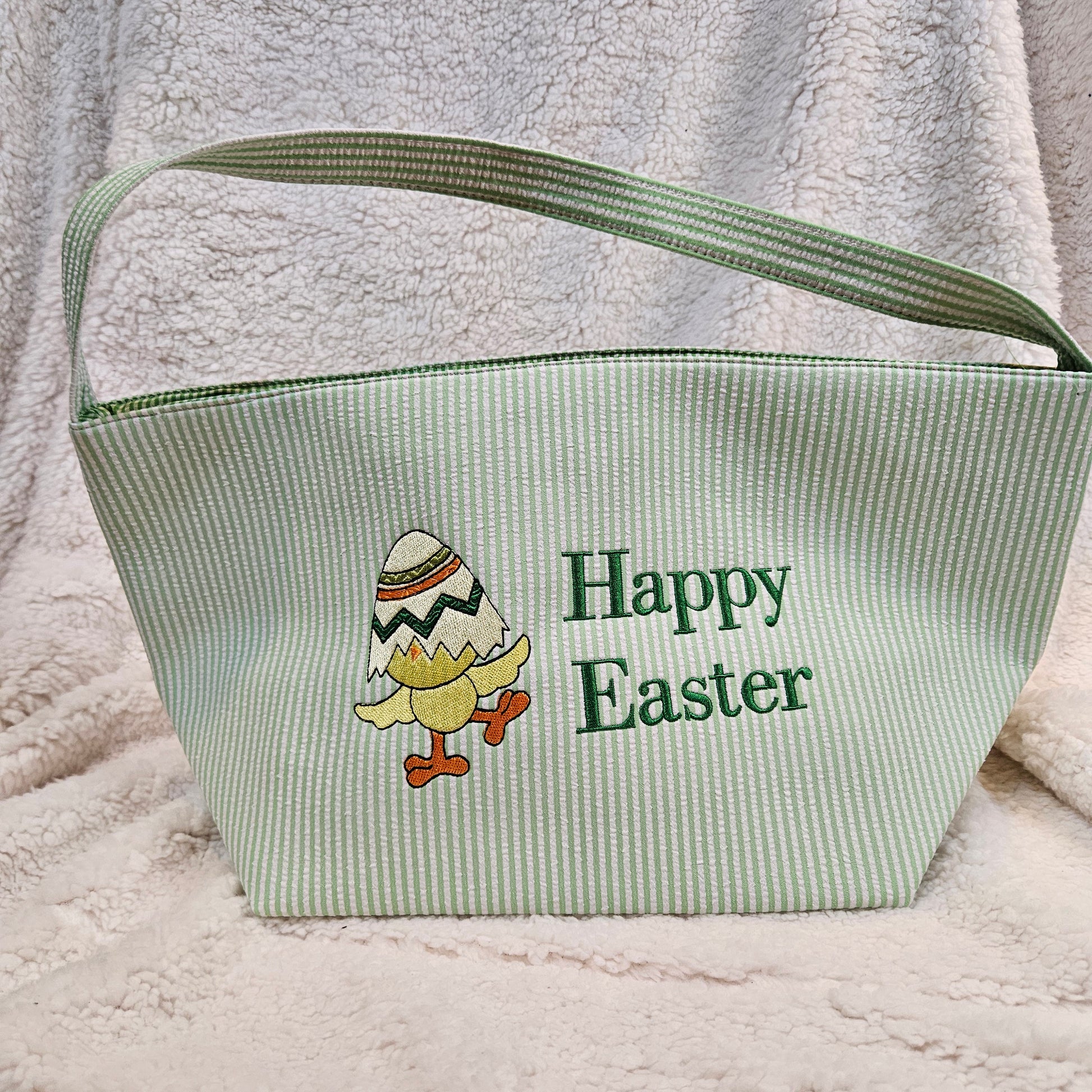 Green stripped basket with 'Happy Easter' text and chick design embroidered on a textured surface