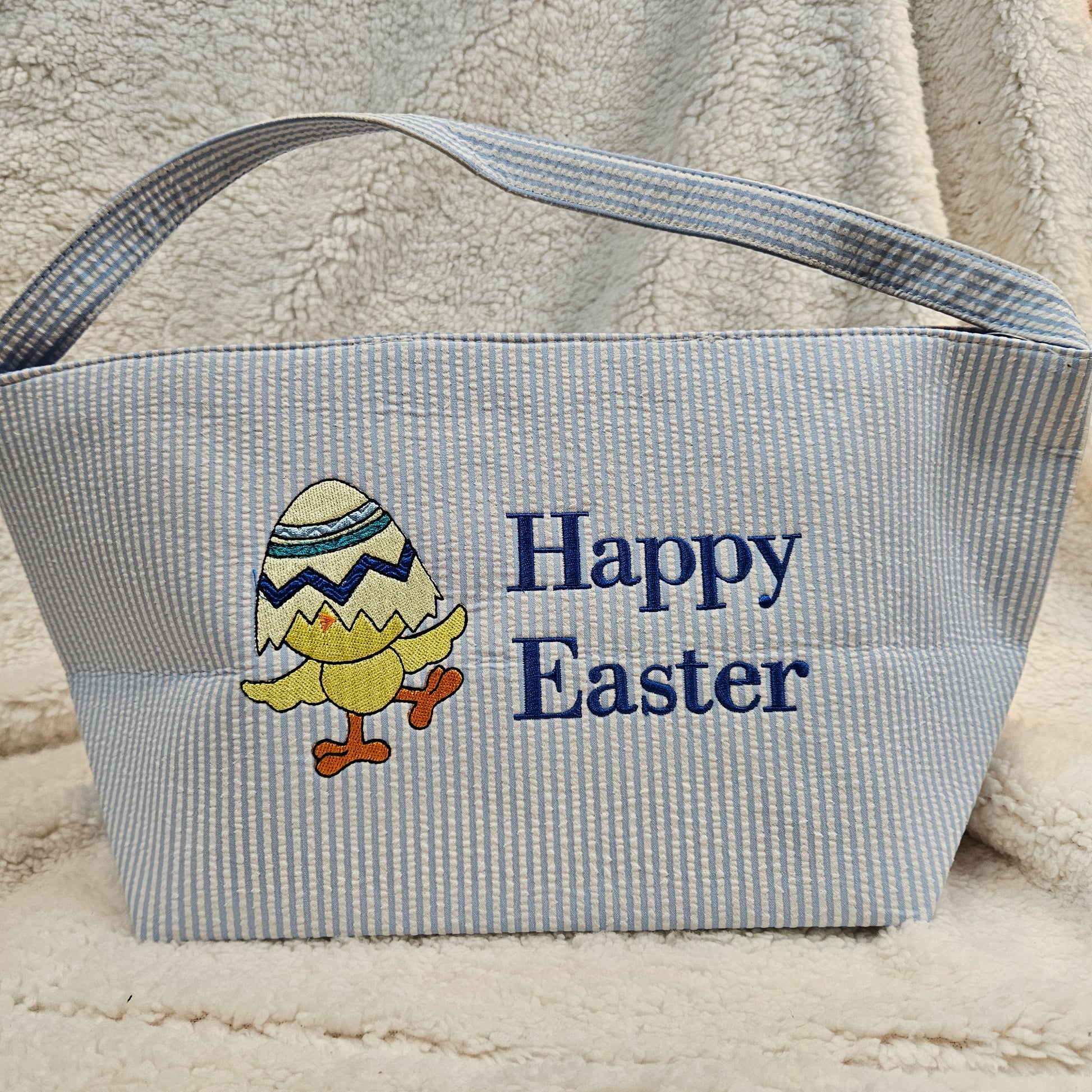 Blue striped bag with 'Happy Easter' text and chick design embroidered on a textured surface