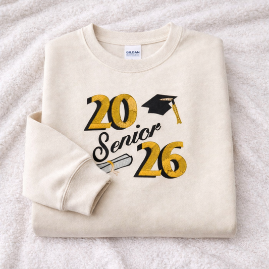 Folded sand sweatshirt with '20 Senior 26' text and graduation cap design on a white background