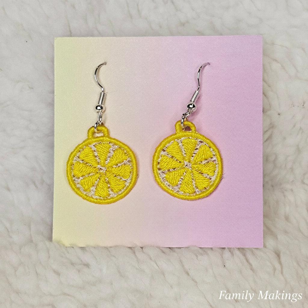 Embroidered lemon slice earrings with silver posts on a card