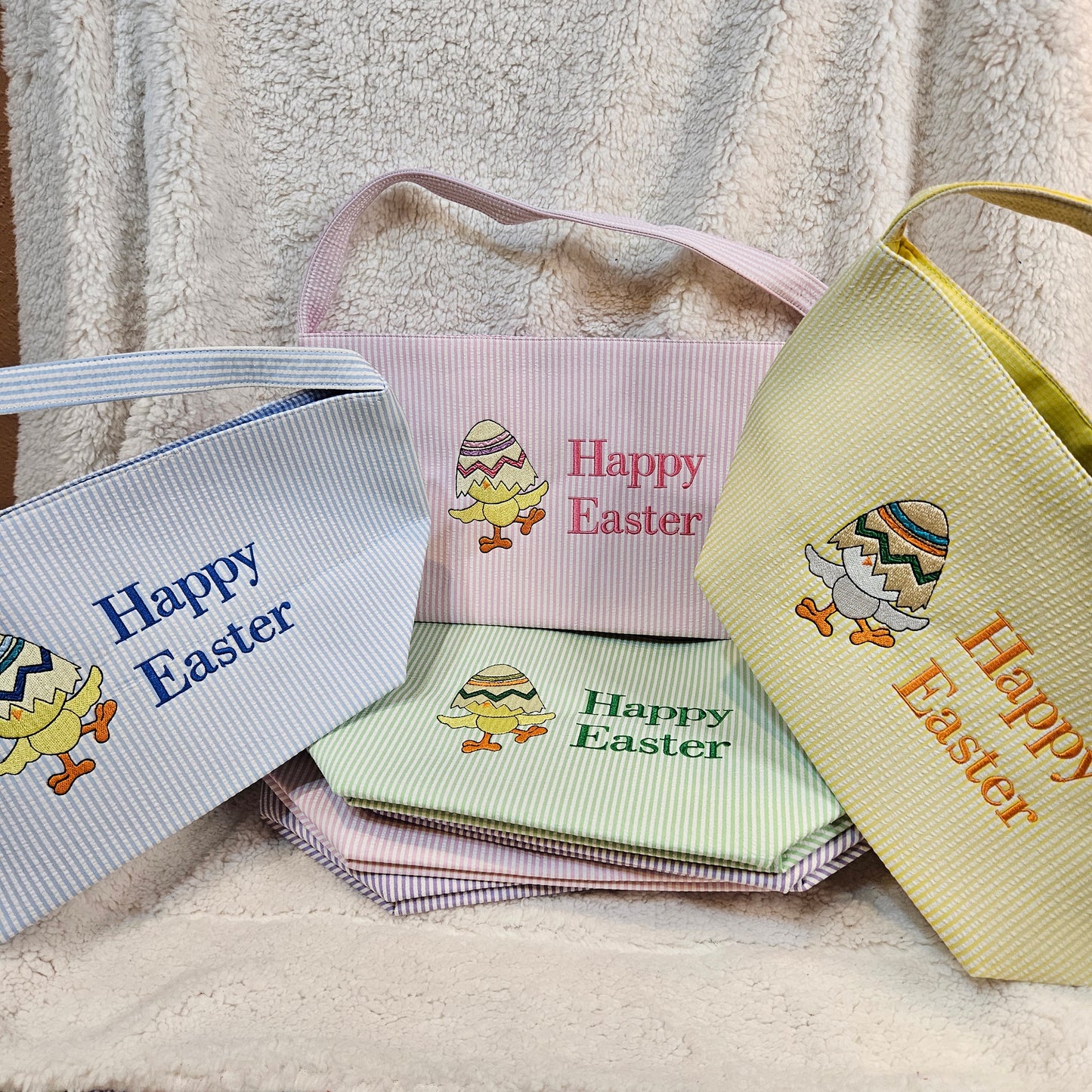 Embroidered 'Happy Easter' baskets with colorful designs on a textured surface.