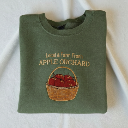 Military green sweatshirt with 'Local & Farm Fresh Apple Orchard' text and apple basket design on a white background