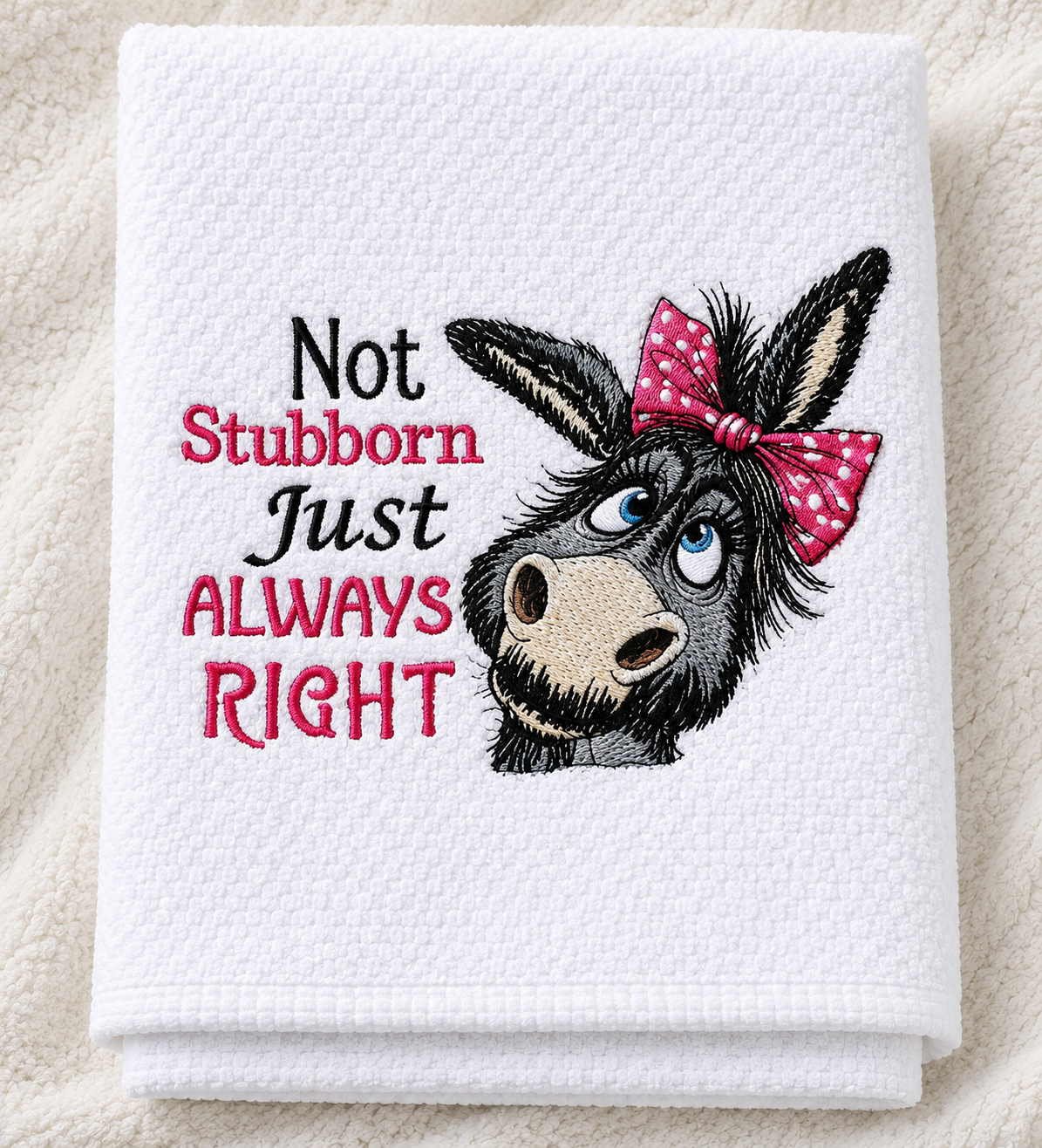 White towel with a donkey illustration and text 'Not Stubborn Just ALWAYS RIGHT' on a textured surface.