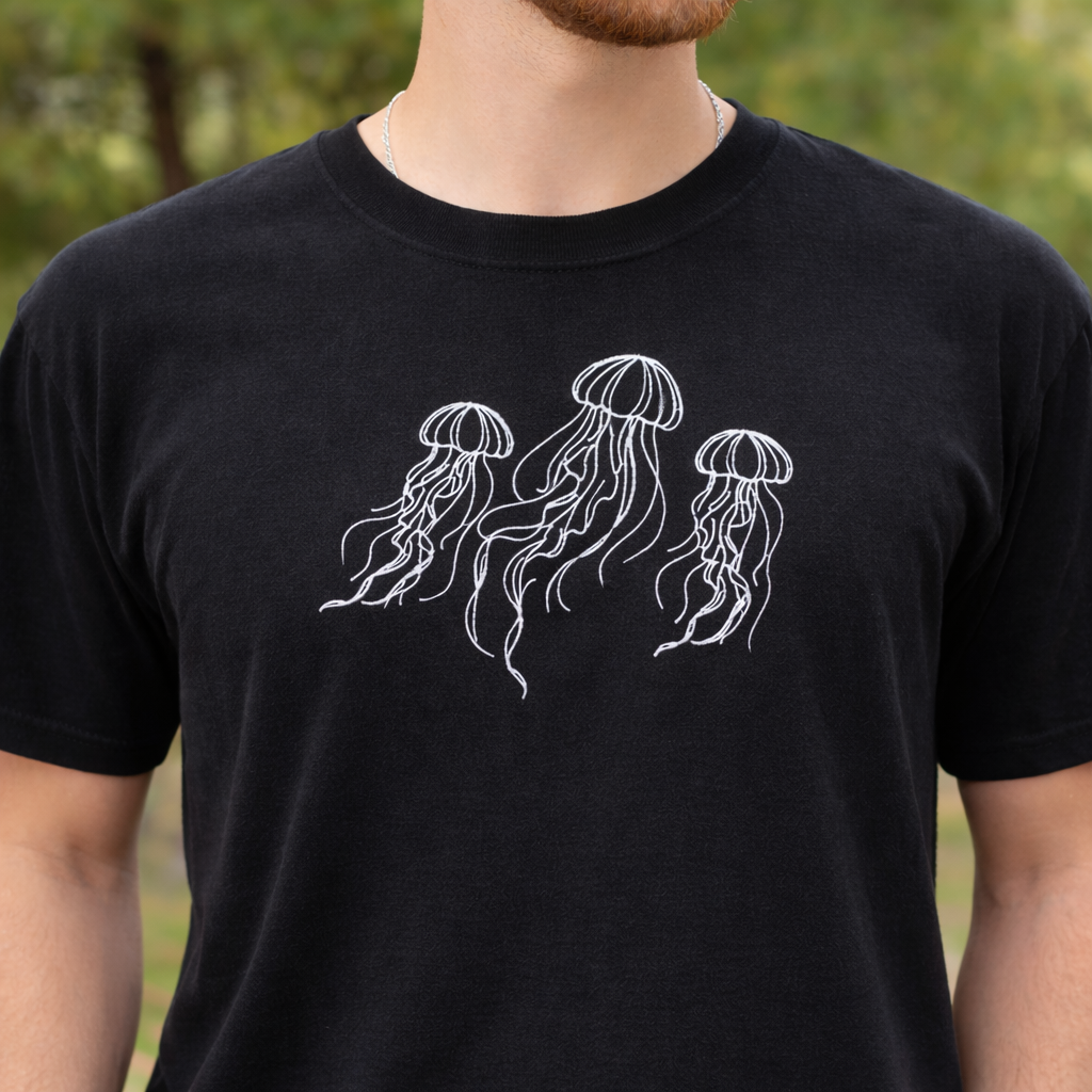 Black t-shirt with white jellyfish design worn by a person outdoors