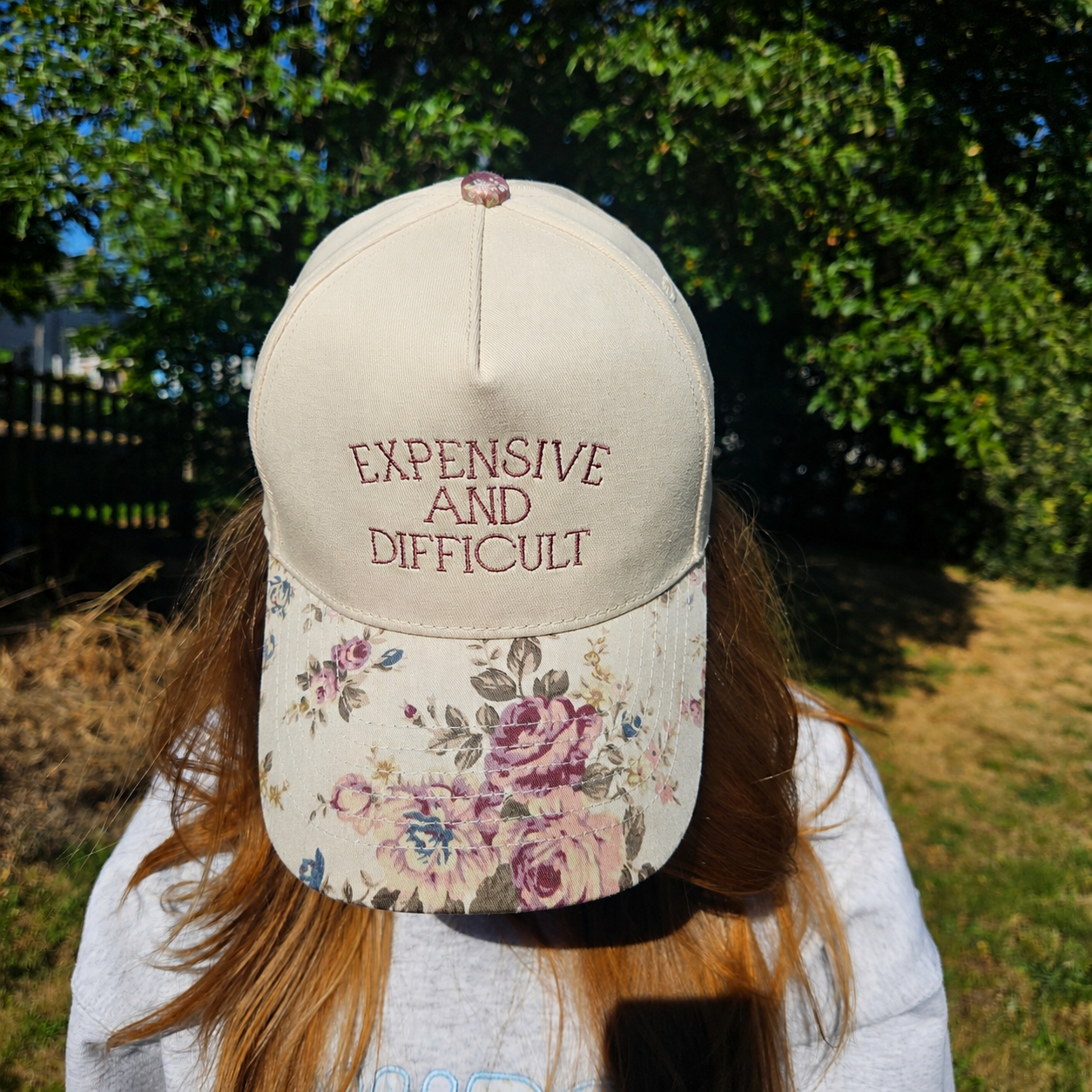 Person wearing a cap with floral design and text outdoors