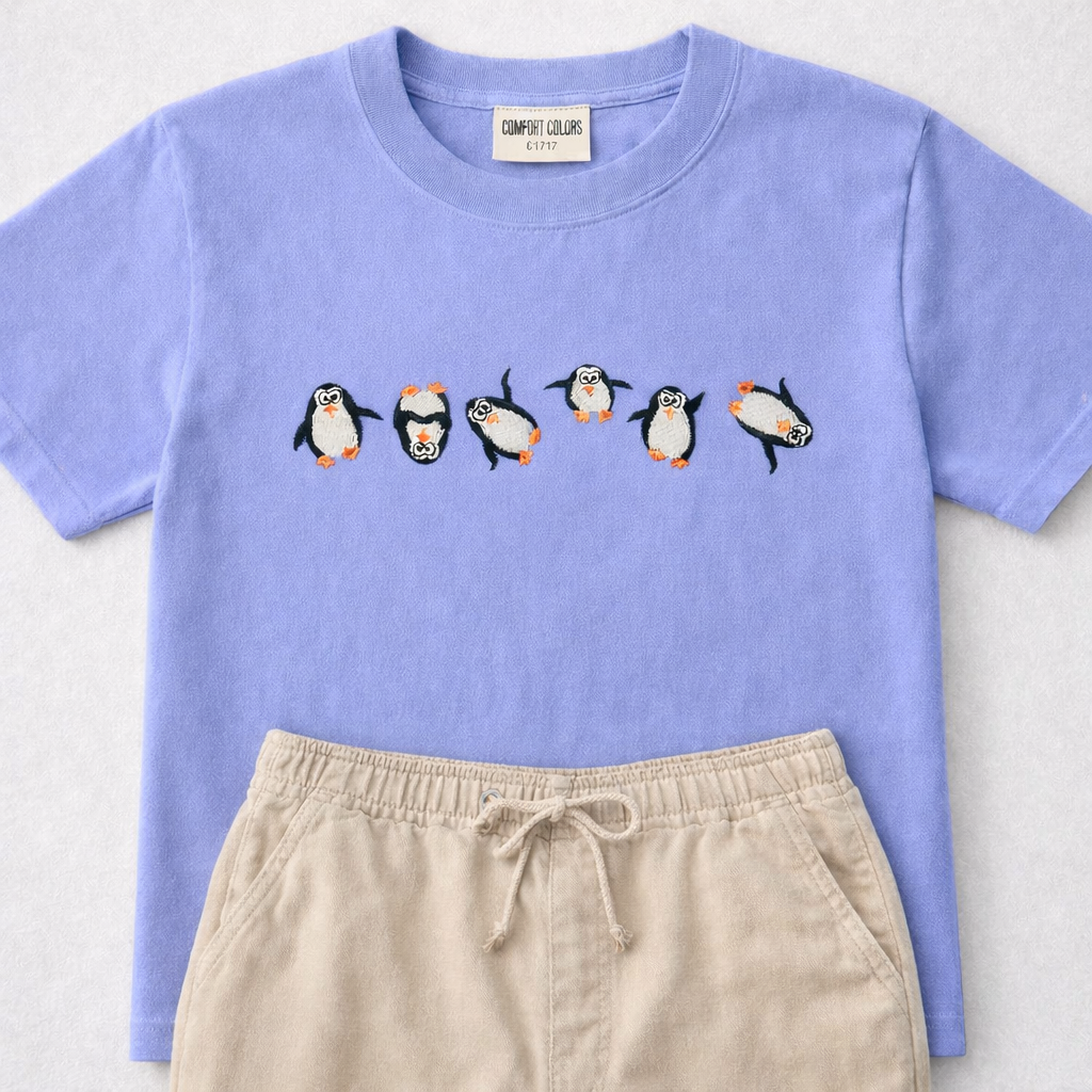 Hydrangea t-shirt with penguin design and beige pants on a light gray background