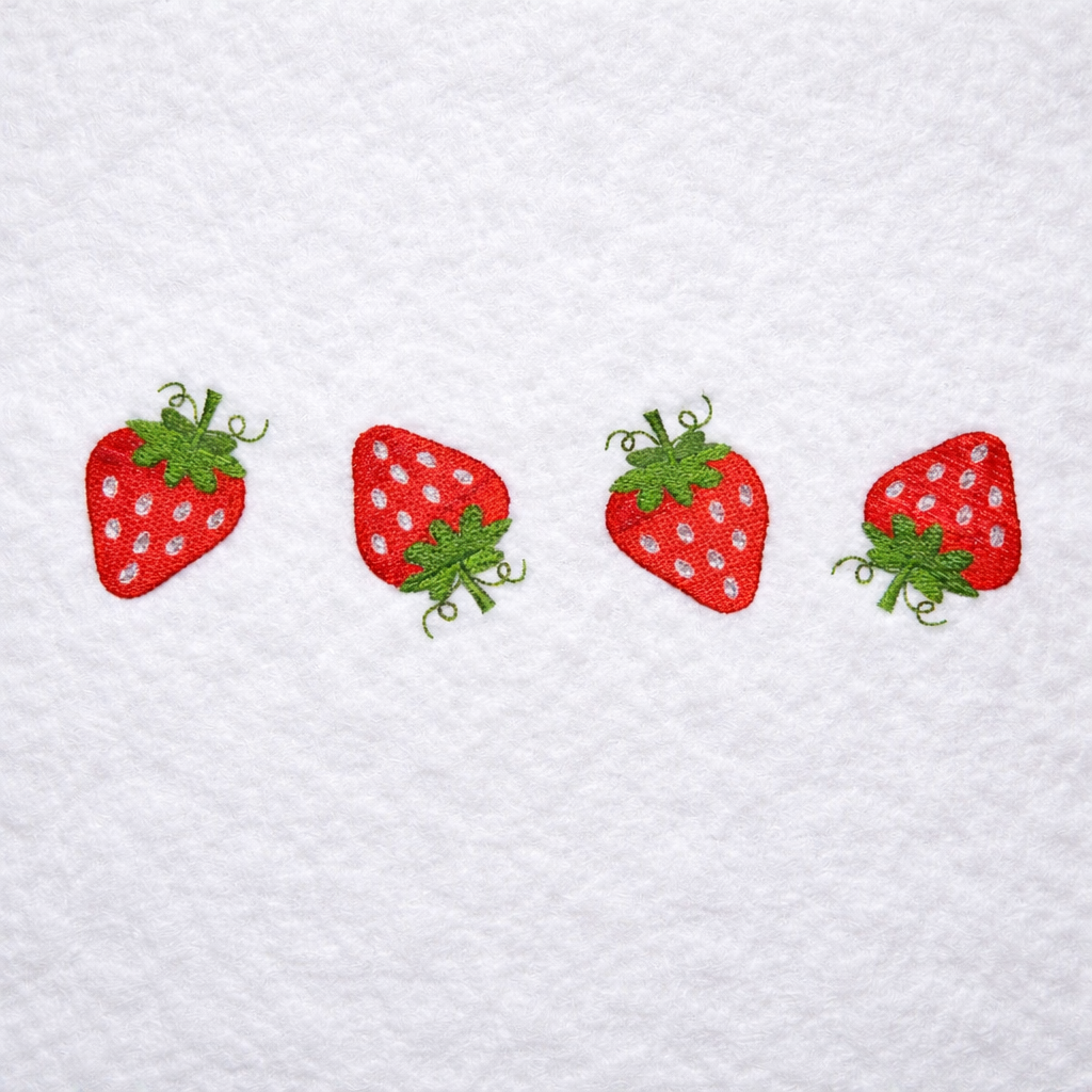 Four embroidered strawberries on a textured white fabric background