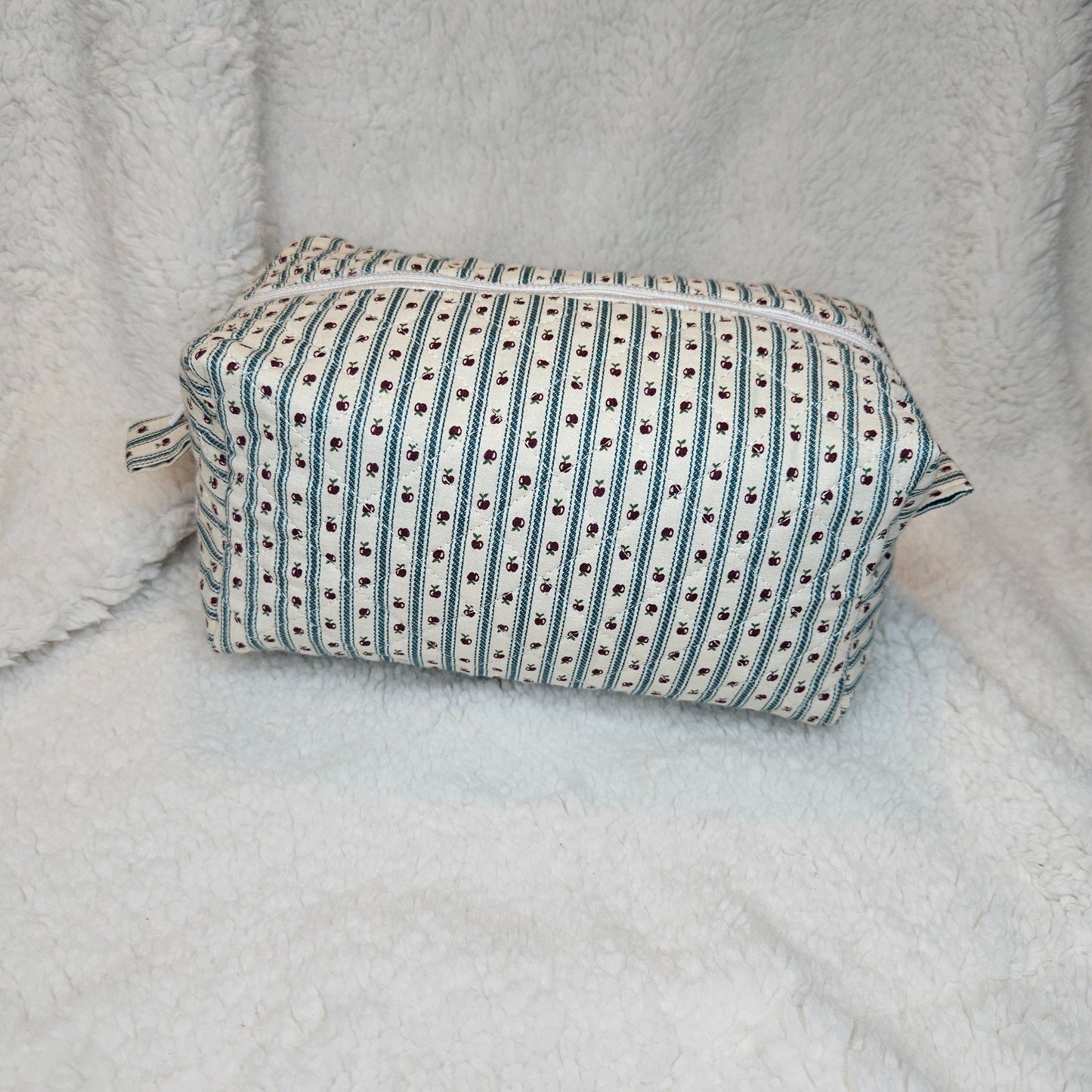 Boxy bag with green and white striped pattern with apples on a textured gray surface
