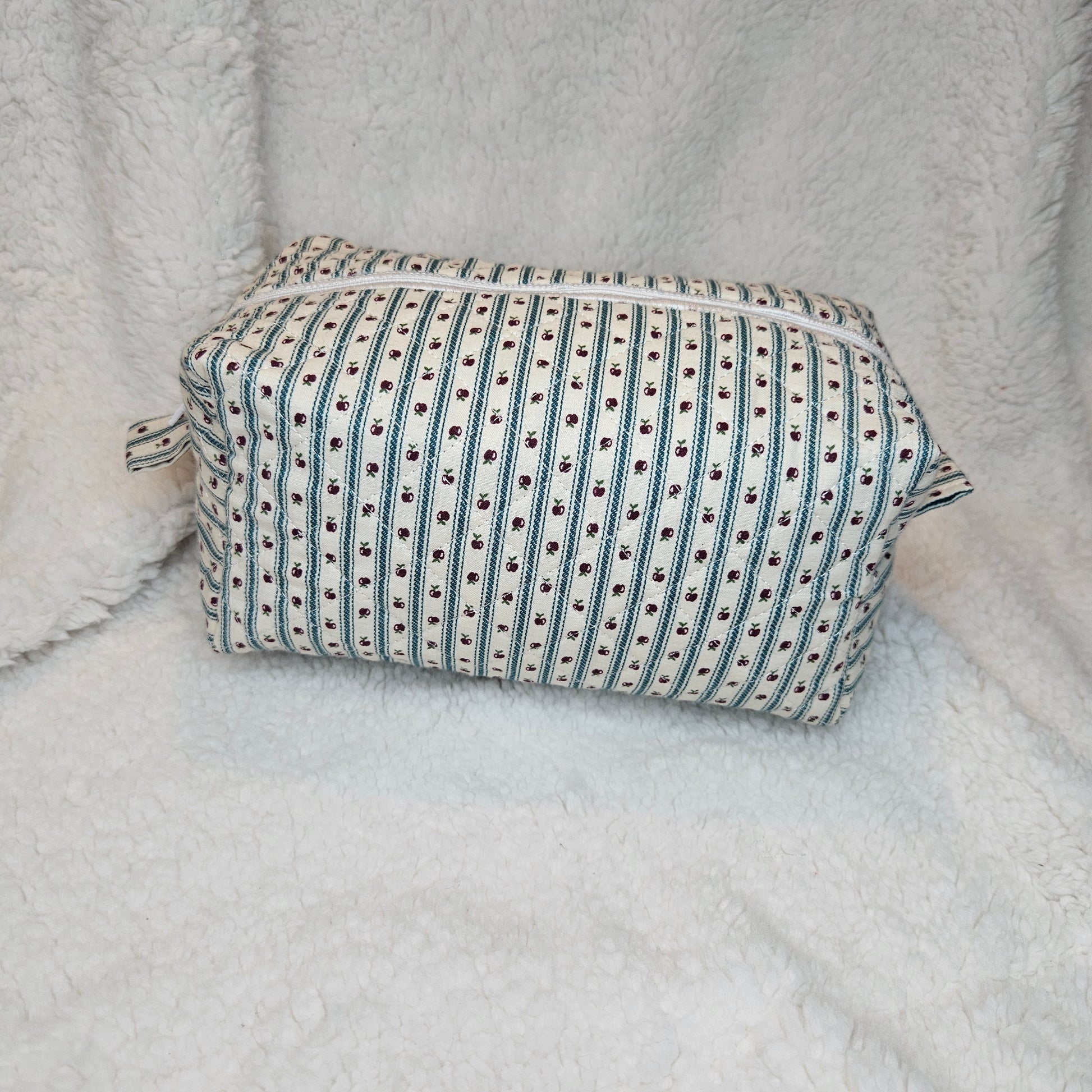 Boxy bag with green and white striped pattern with apples on a textured gray surface