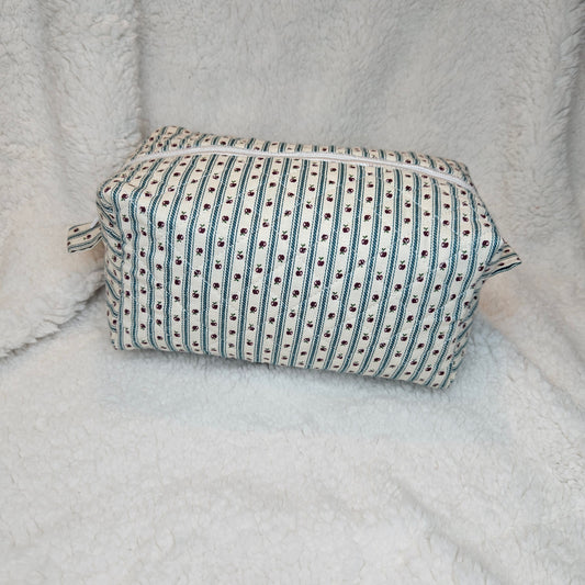 Boxy bag with green and white striped pattern with apples on a textured gray surface