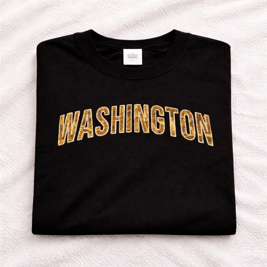 Black t-shirt with applique 'WASHINGTON' embroidered in beige on a white textured background
