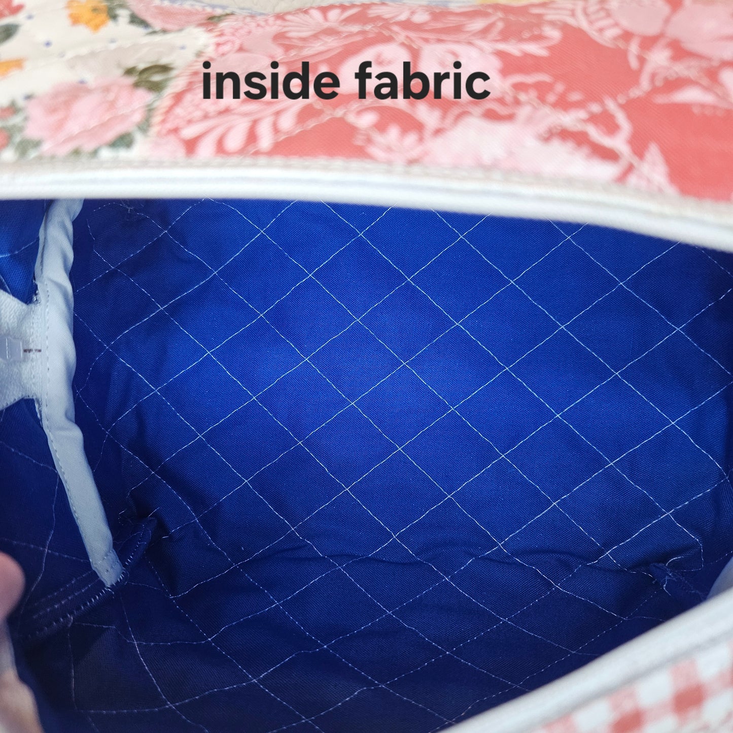 Close-up of blue quilted fabric inside bag with floral fabric visible above.