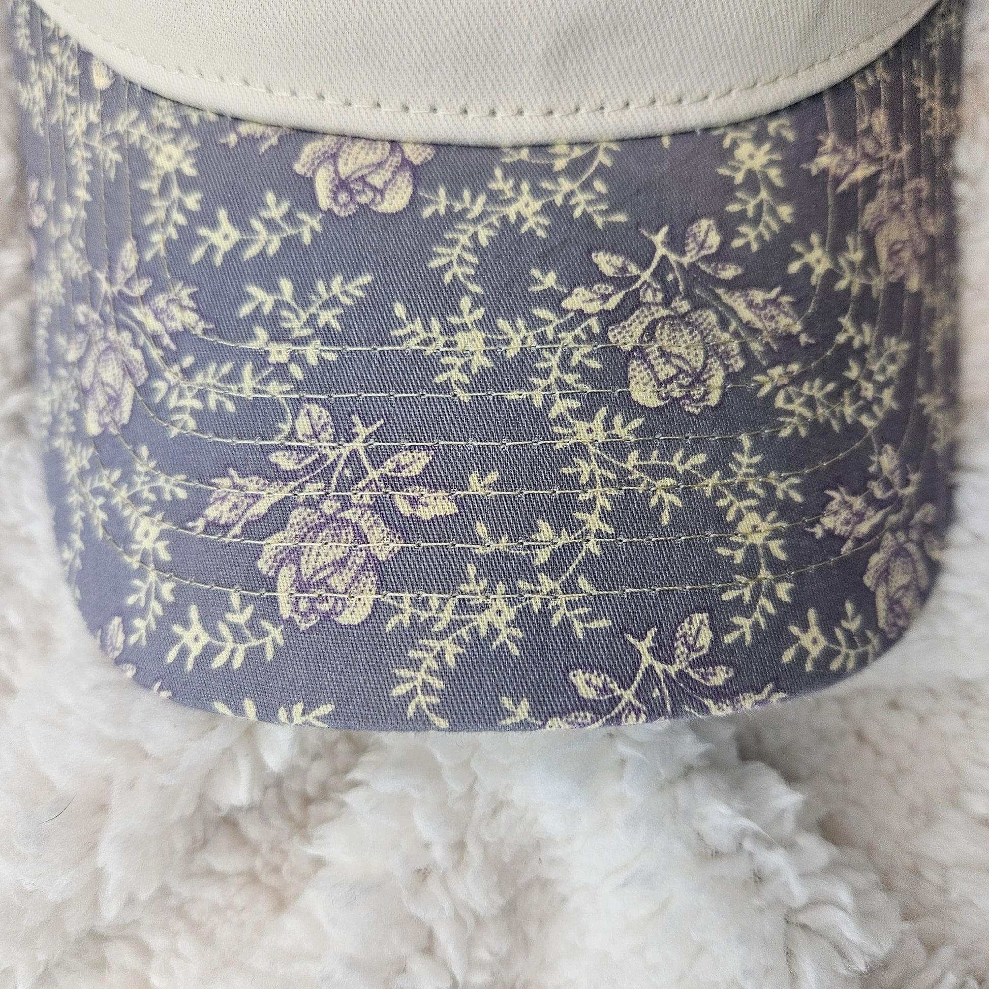 Floral patterned hat bill on a textured surface
