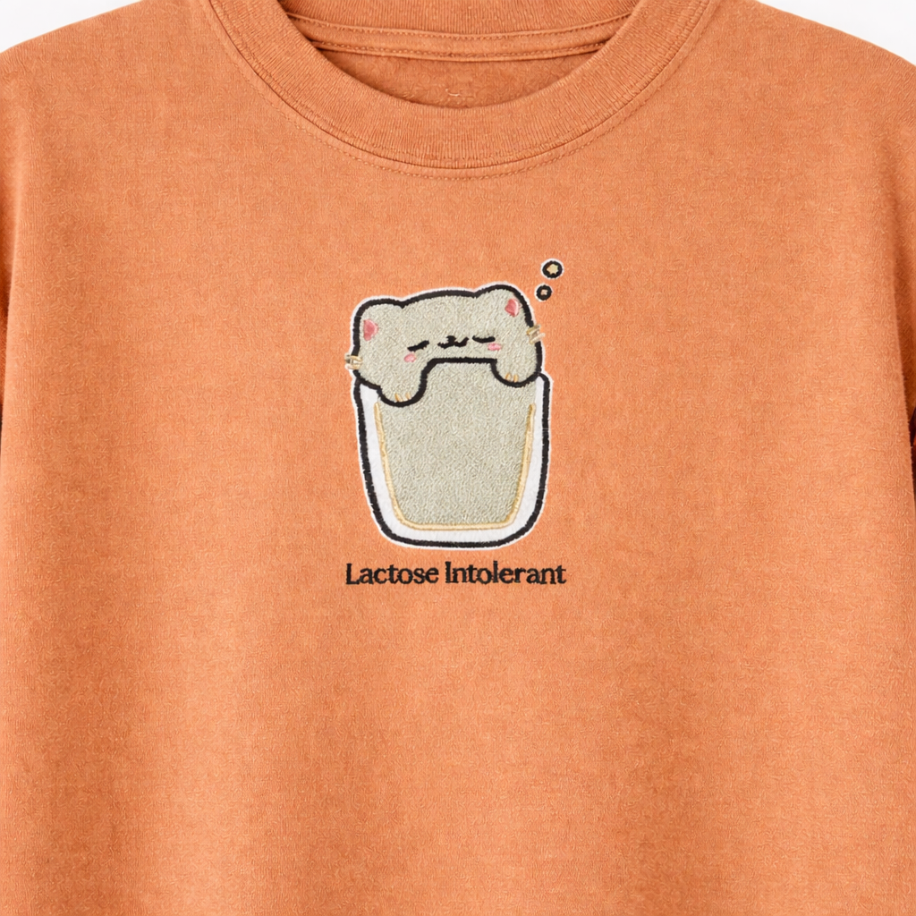 Yam t-shirt with an embroidered cartoon cat and text 'Lactose Intolerant' on a plain background