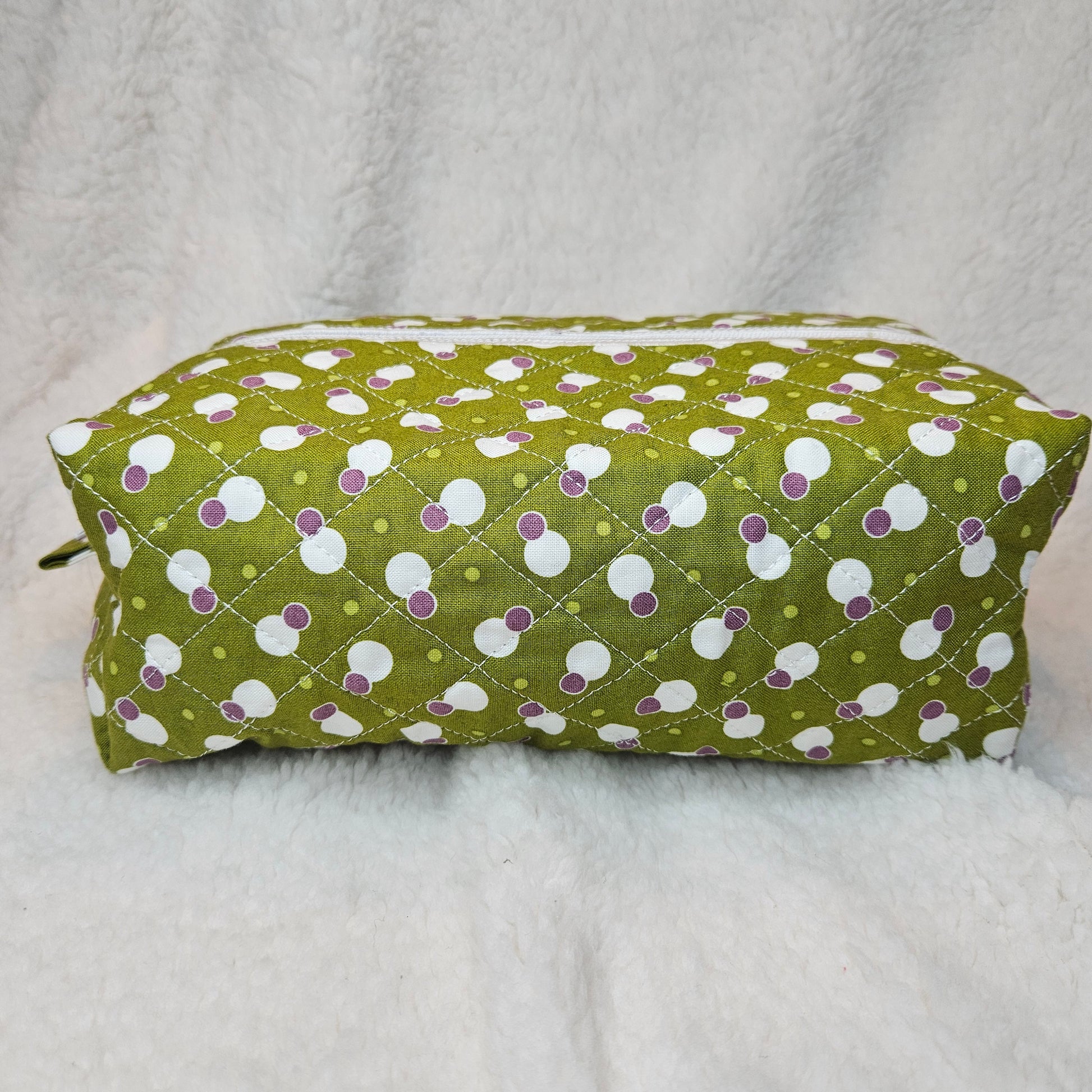 Green bag with white and purple polka dot pattern on a gray background