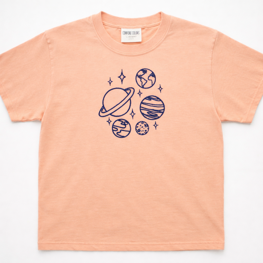 Peachy t-shirt with space-themed embroidered design on a white background