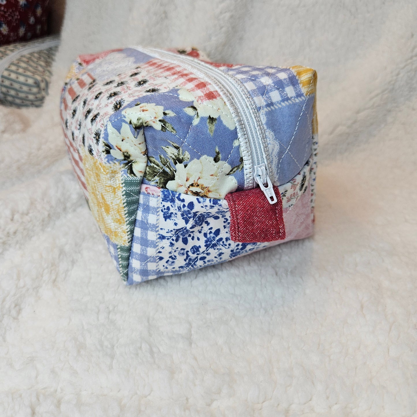 Quilted fabric pouch with floral pattern on a textured surface