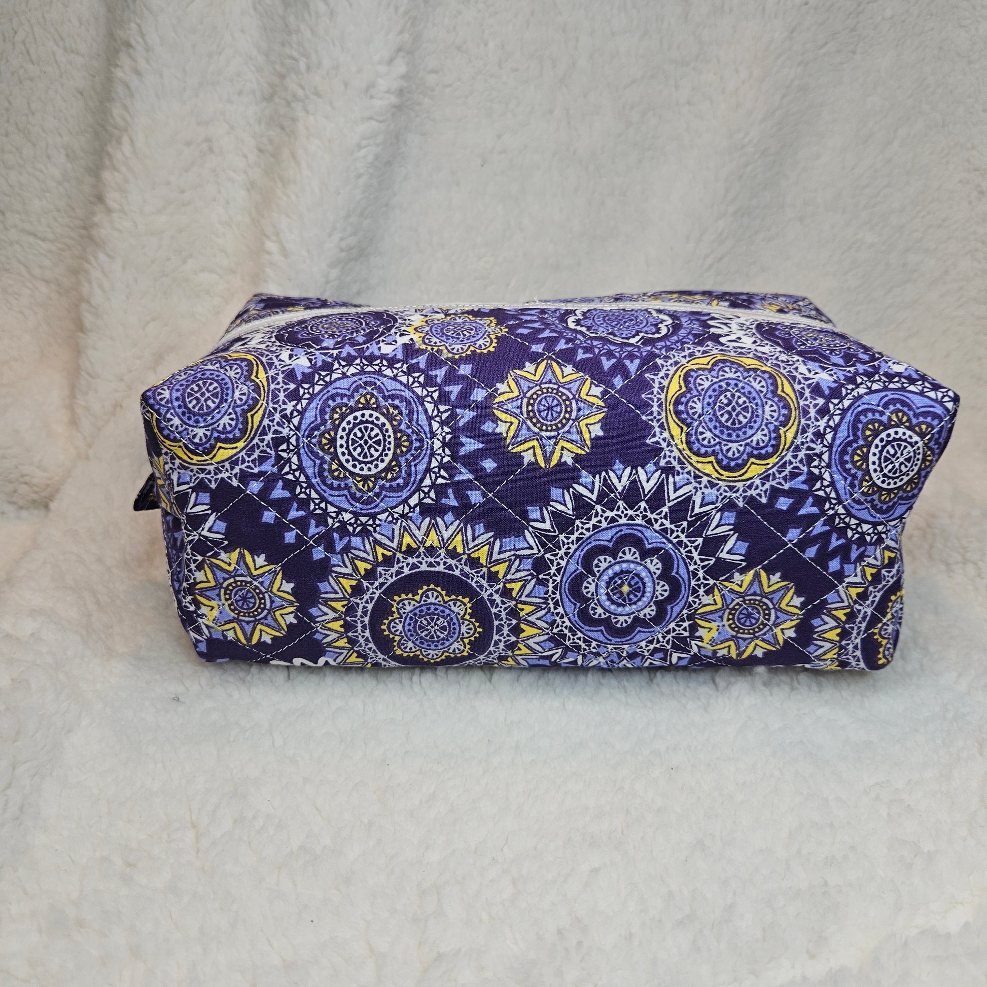 Boxy bag with purple and yellow pattern on a white blanket