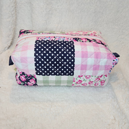 Patchwork bag with floral, checkered, and polka dot patterns on a textured surface.