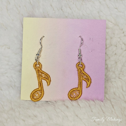 Gold colored Eighth note embroidered earrings on a card