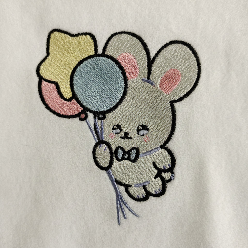 Embroidered design of a bunny holding balloons on a white background