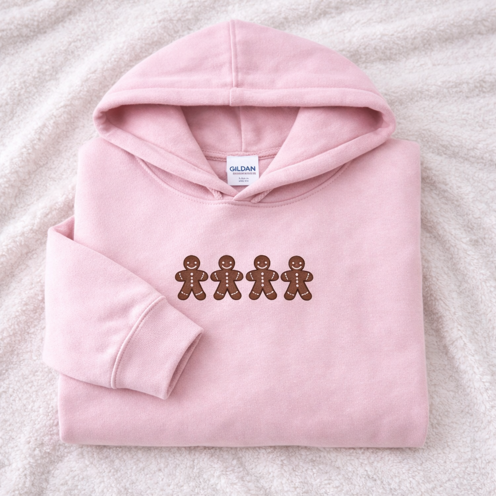 Light pink hoodie with gingerbread man design on a white suface