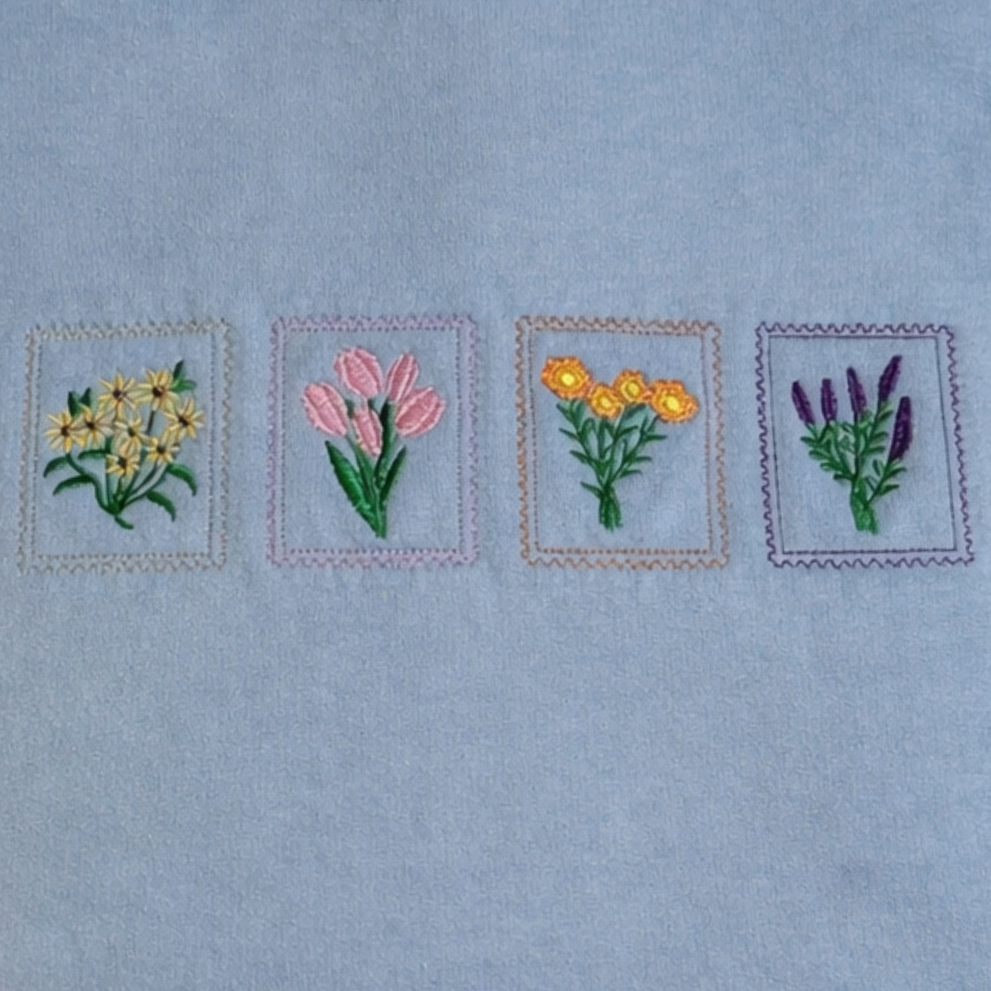 Four embroidered floral designs on a light blue fabric background