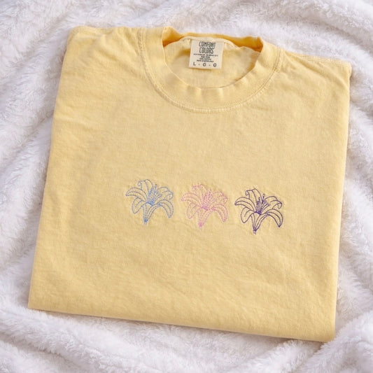 Folded butter t-shirt with floral embroidery on a white blanket