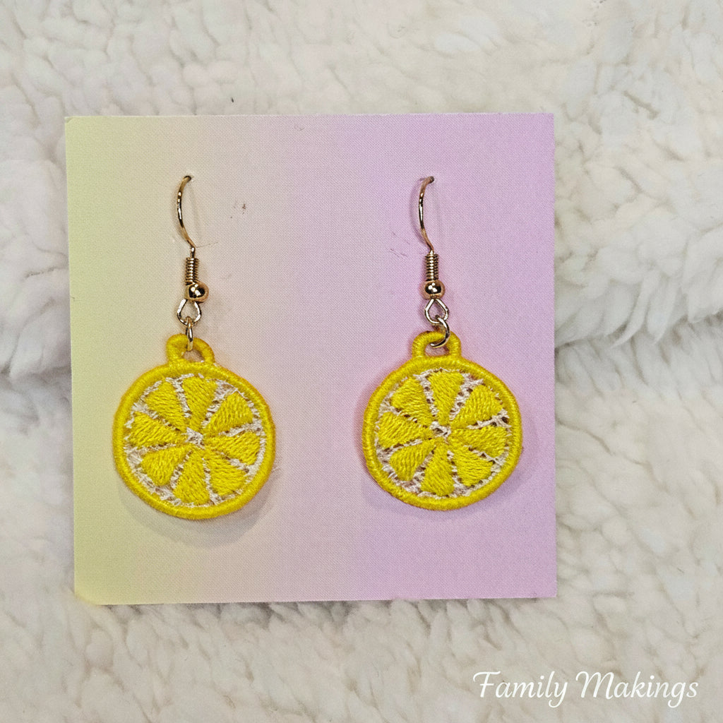 Embroidered lemon slice earrings with gold posts on a card