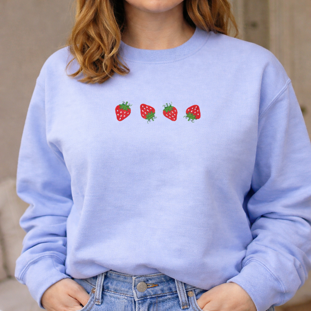Person wearing a light blue sweatshirt with strawberry designs.