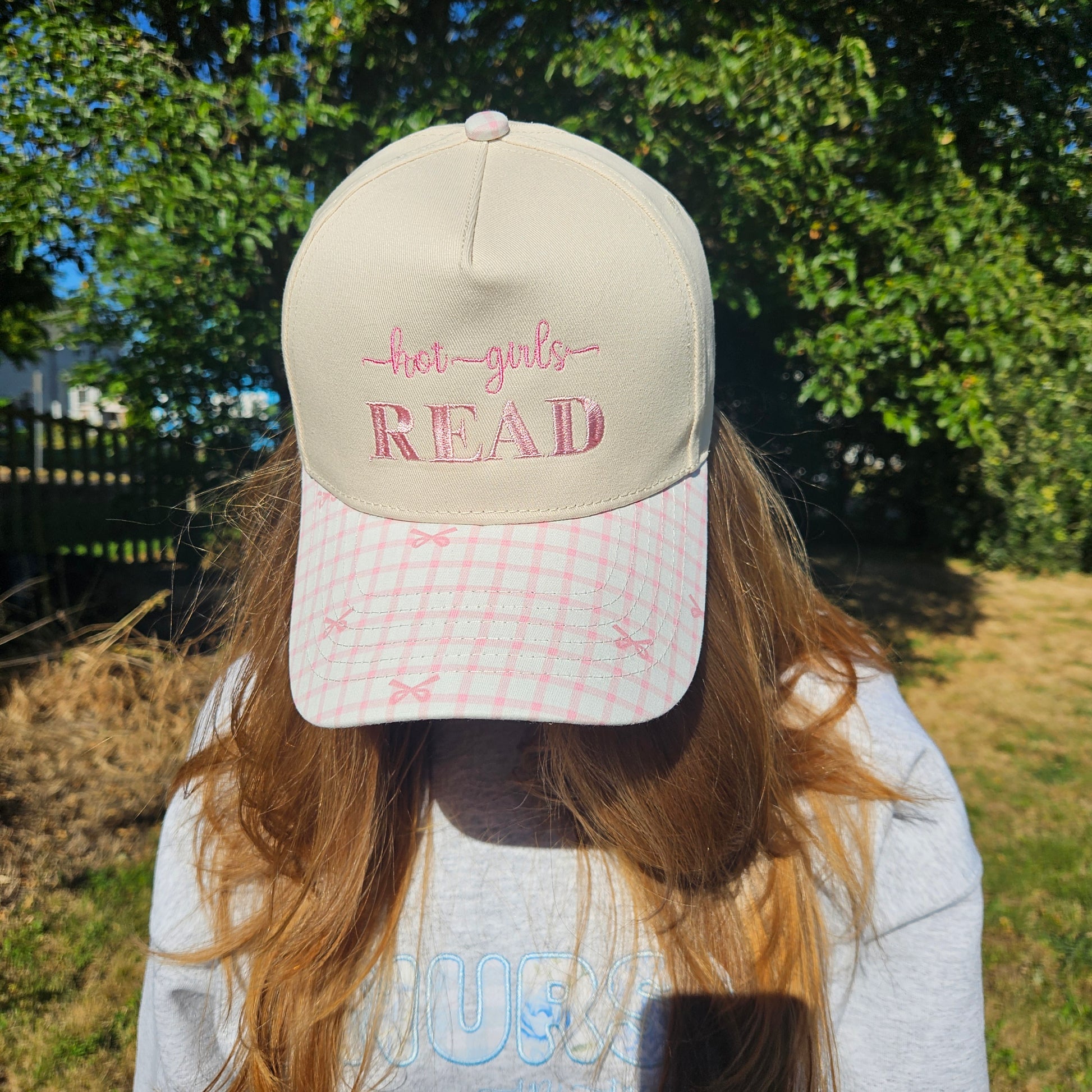 Person wearing a cap with 'hot girls, read' text outdoors