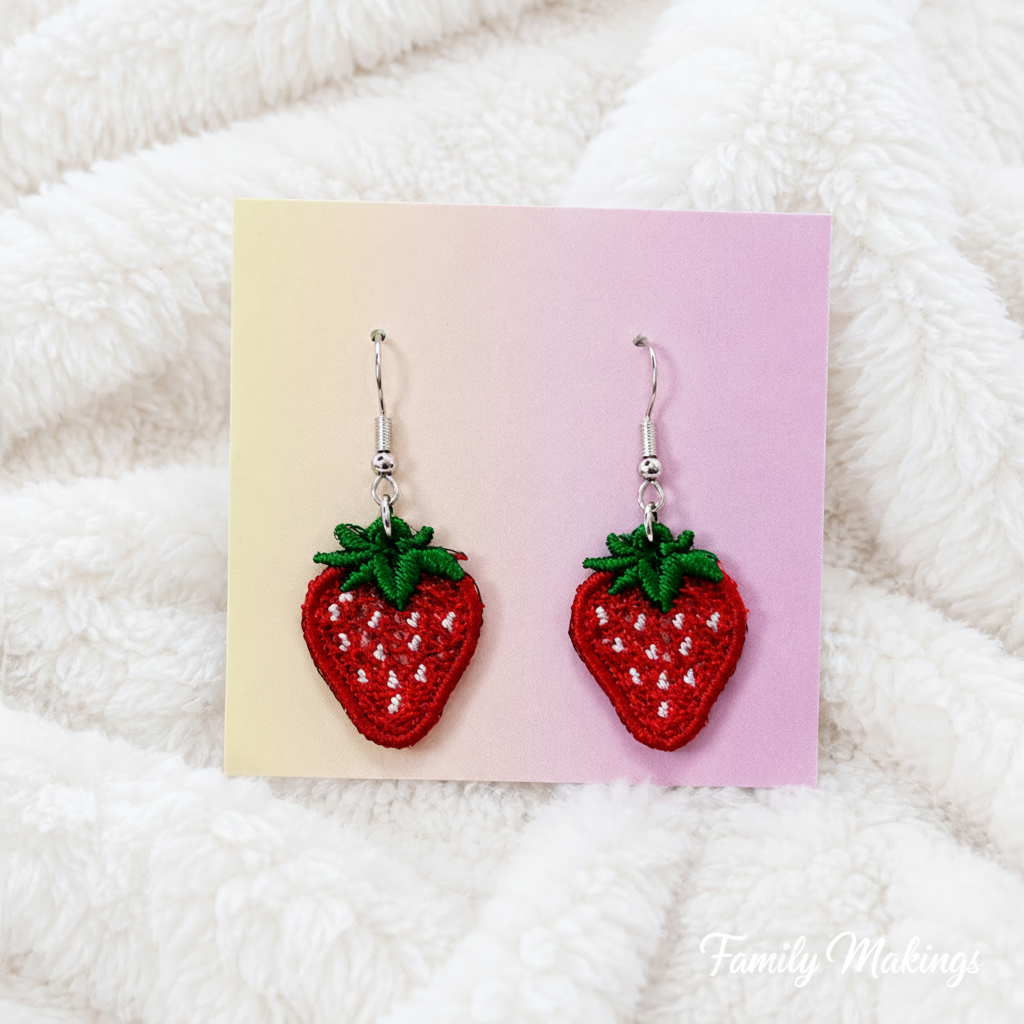 Embroidered strawberry earrings with silver posts on a card