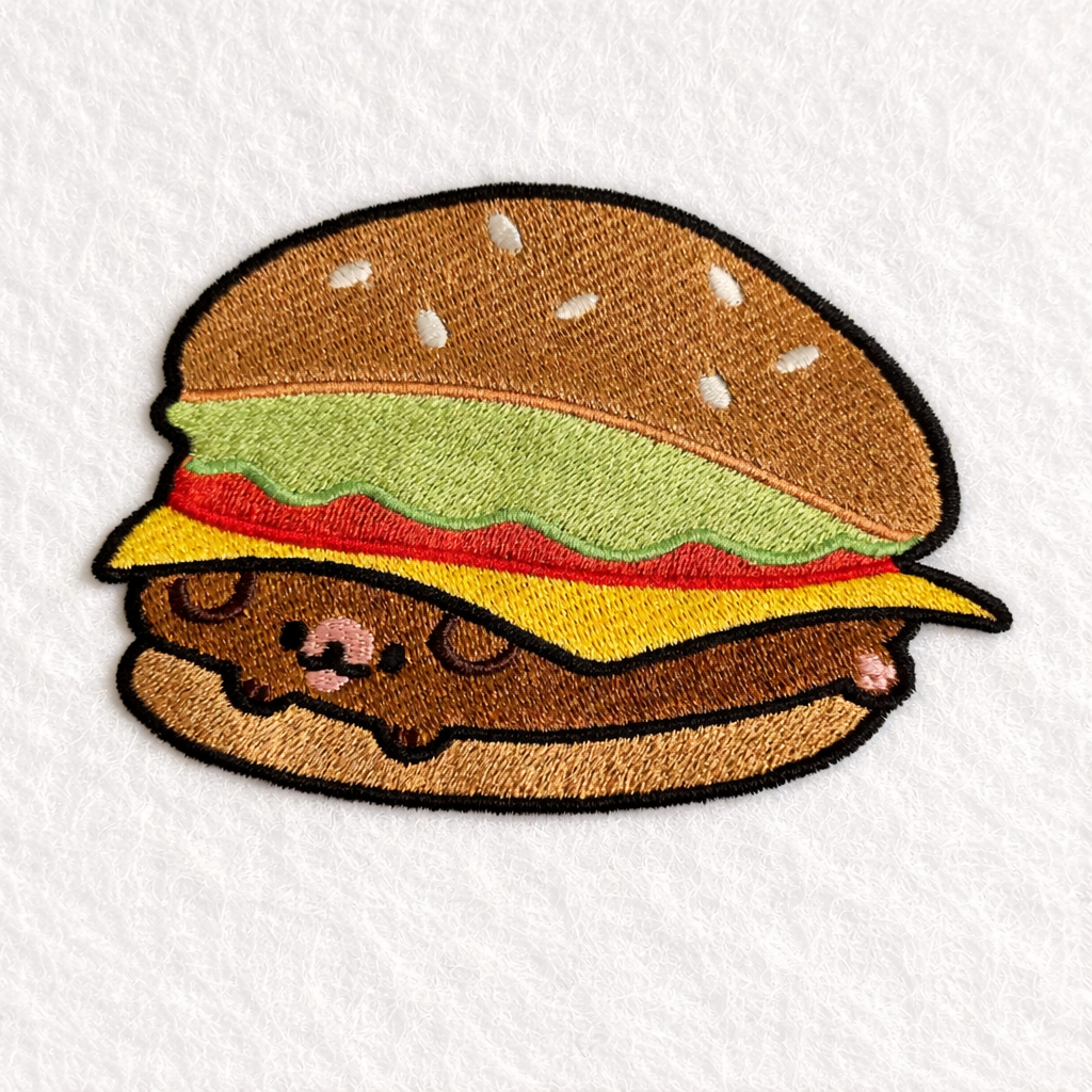 Embroidered design of a cartoonish hamburger on a white background